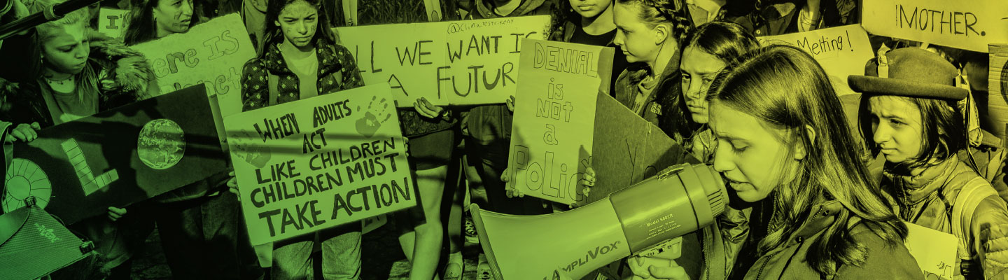 A girl with a megaphone in front of a crowd of kids holding signs