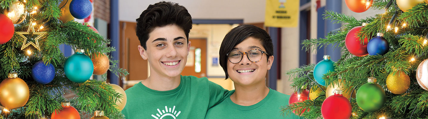 Image of two students posing next to Christmas tree with ornaments